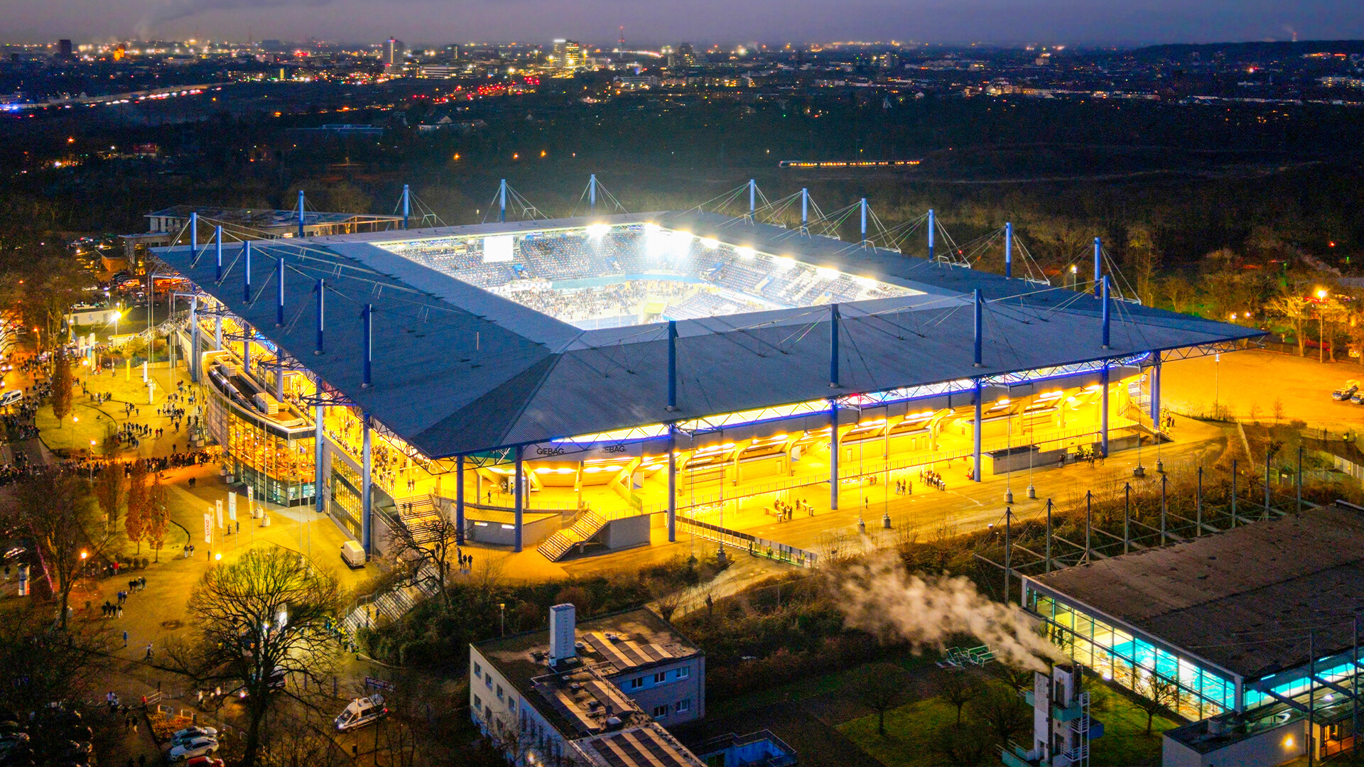 Aufnahme von oben und außen auf das nachts illuminierte Stadion