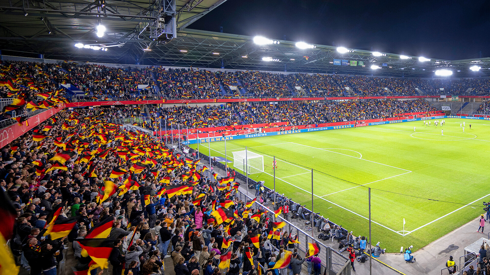 Einblick in das Duisburger Stadion, links die Sitzränge mit vielen Deutschland-Fahnen, rechts der Rasen.